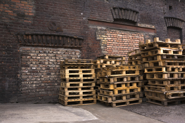 Wooden pallets are stacked in the yard of the old warehouse.